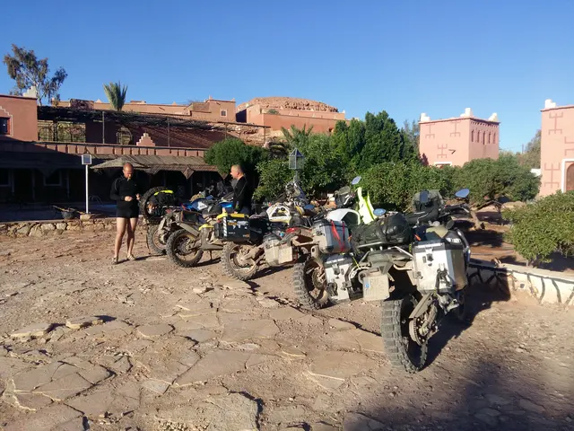 Trzy motocykle z jeźdźcami przed budynkami w pustynnym stylu.
