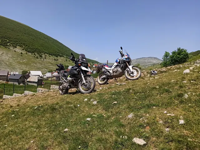 Enduro motorky na kopci s výhledem na horskou vesnici.