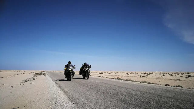 Zwei Motorradfahrer auf einer Wüstenstraße, Enduro-Reise in den Senegal.
