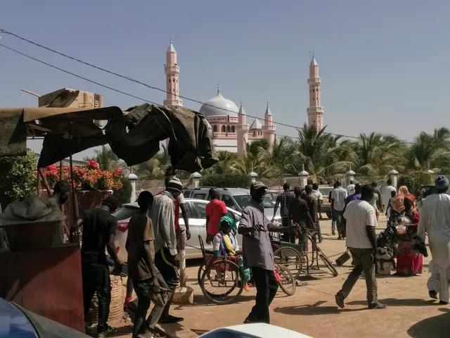 Belebte Straße im Senegal mit Menschen und einer Moschee im Hintergrund