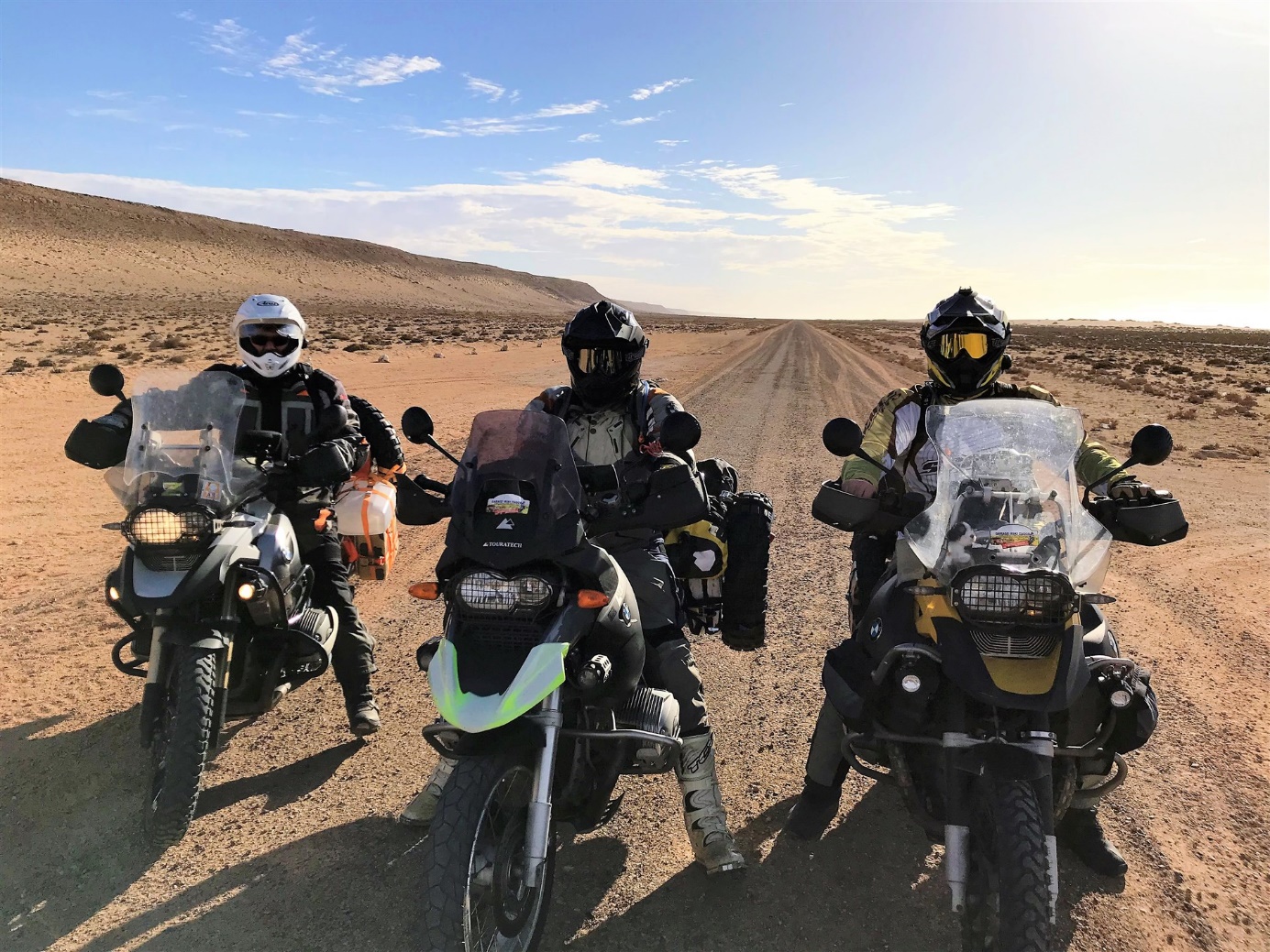 Tři motorkáři na BMW GS na písečné cestě v Západní Sahaře
